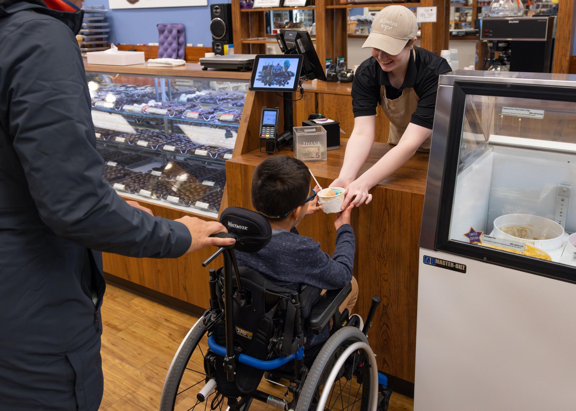 A-boy-in-a-wheelchair-being-handed-a-cup-of-ice-cream