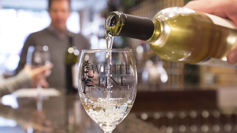 A glass of white wine being poured at White Pine Winery