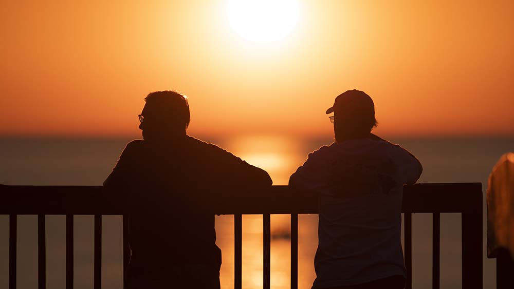 two people enjoying the view of the sunset from the John and Dede Howard Family Recreational Trail.