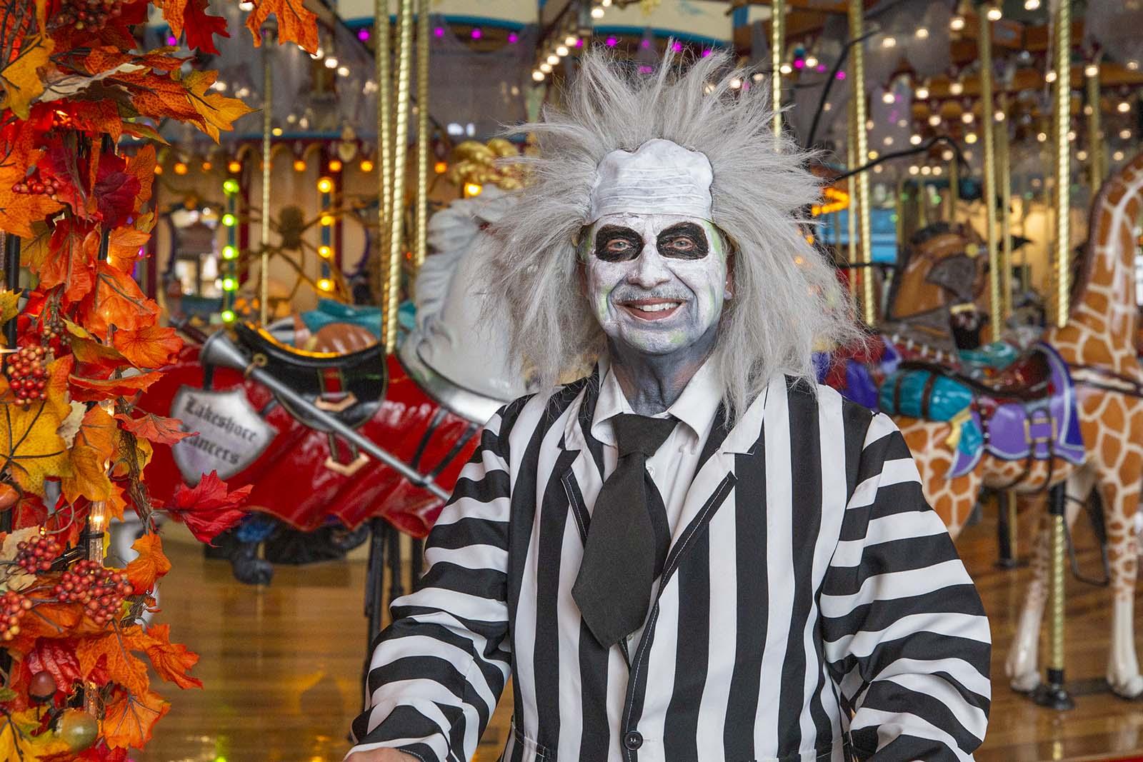 A person in a costume standing in front of the Haunted Scarousel.