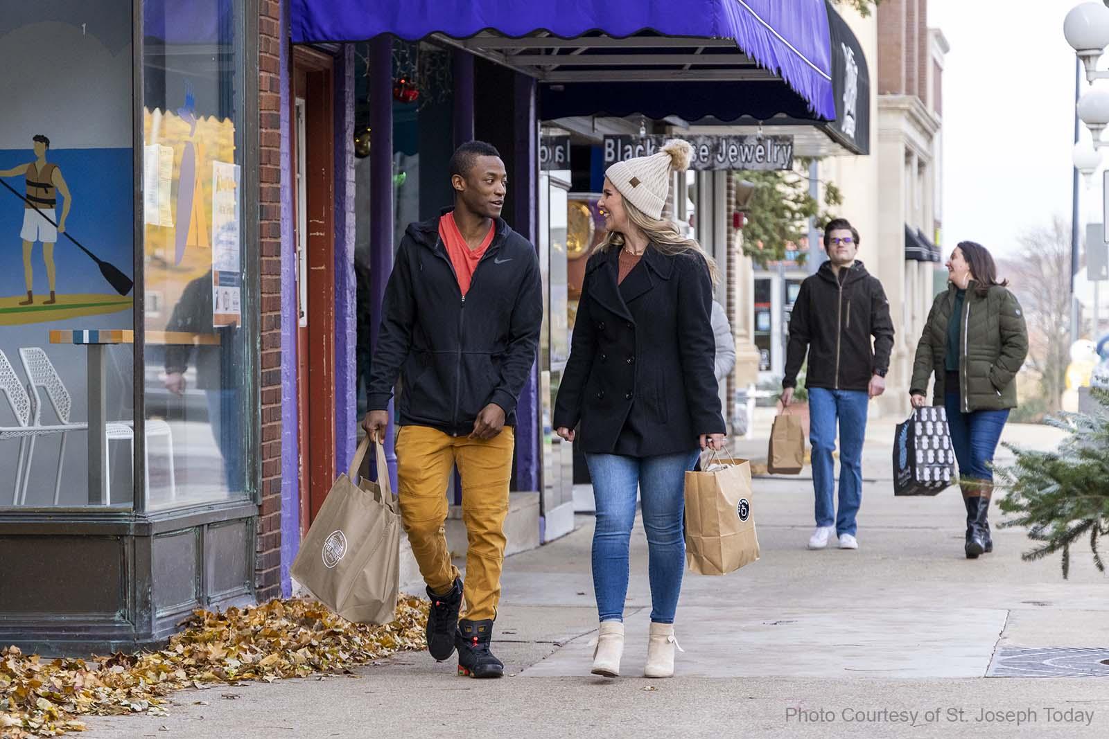 People walking in downtown St. Joseph carrying shopping bags.