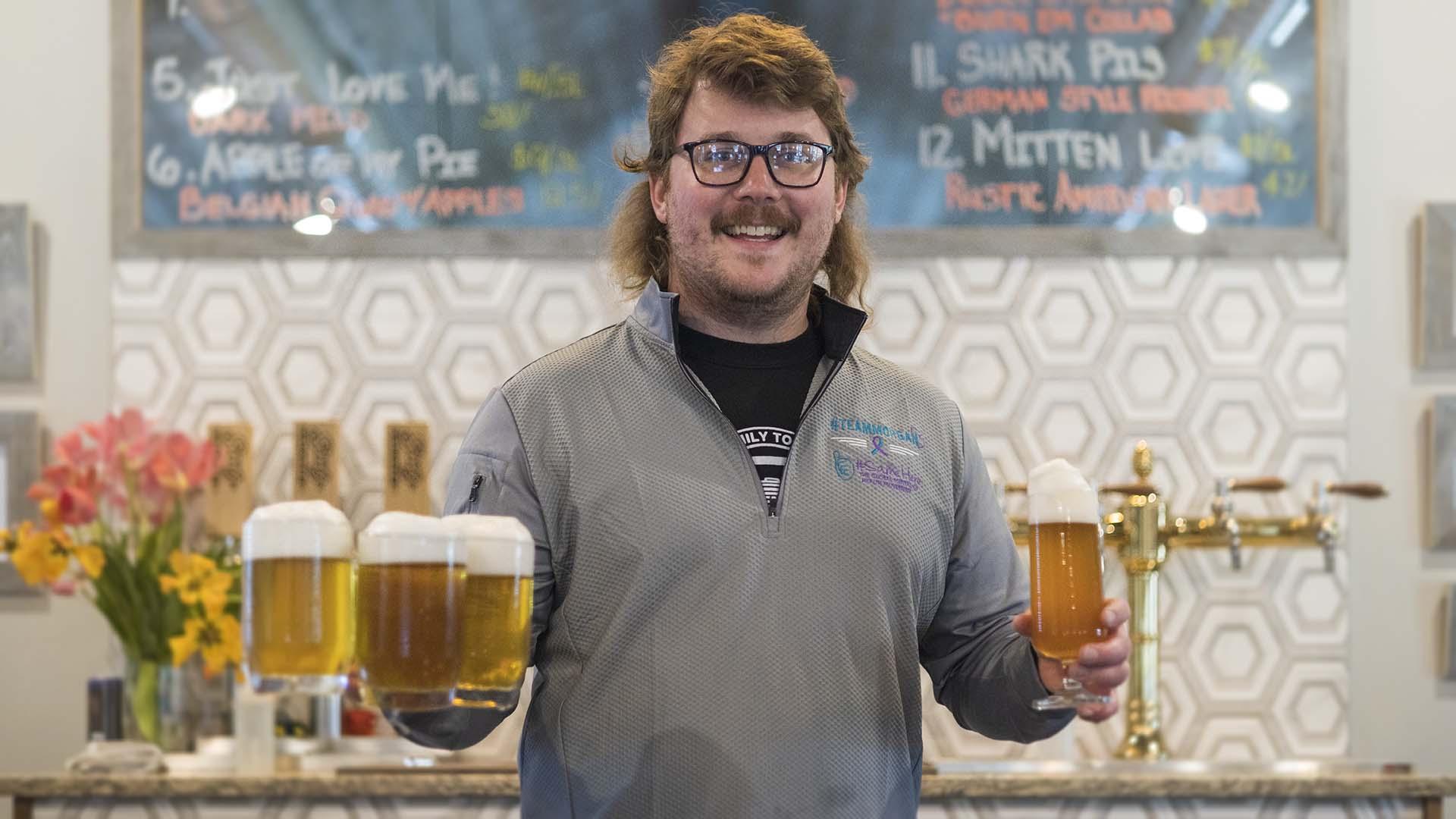 The owner and brewer at Seedz Brewery holding beers. 