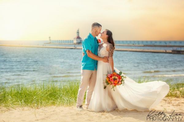 Wedding photo of a couple at Silver Beach with the lighthouse in the background.