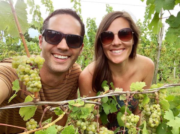 Two people standing in a vineyard.