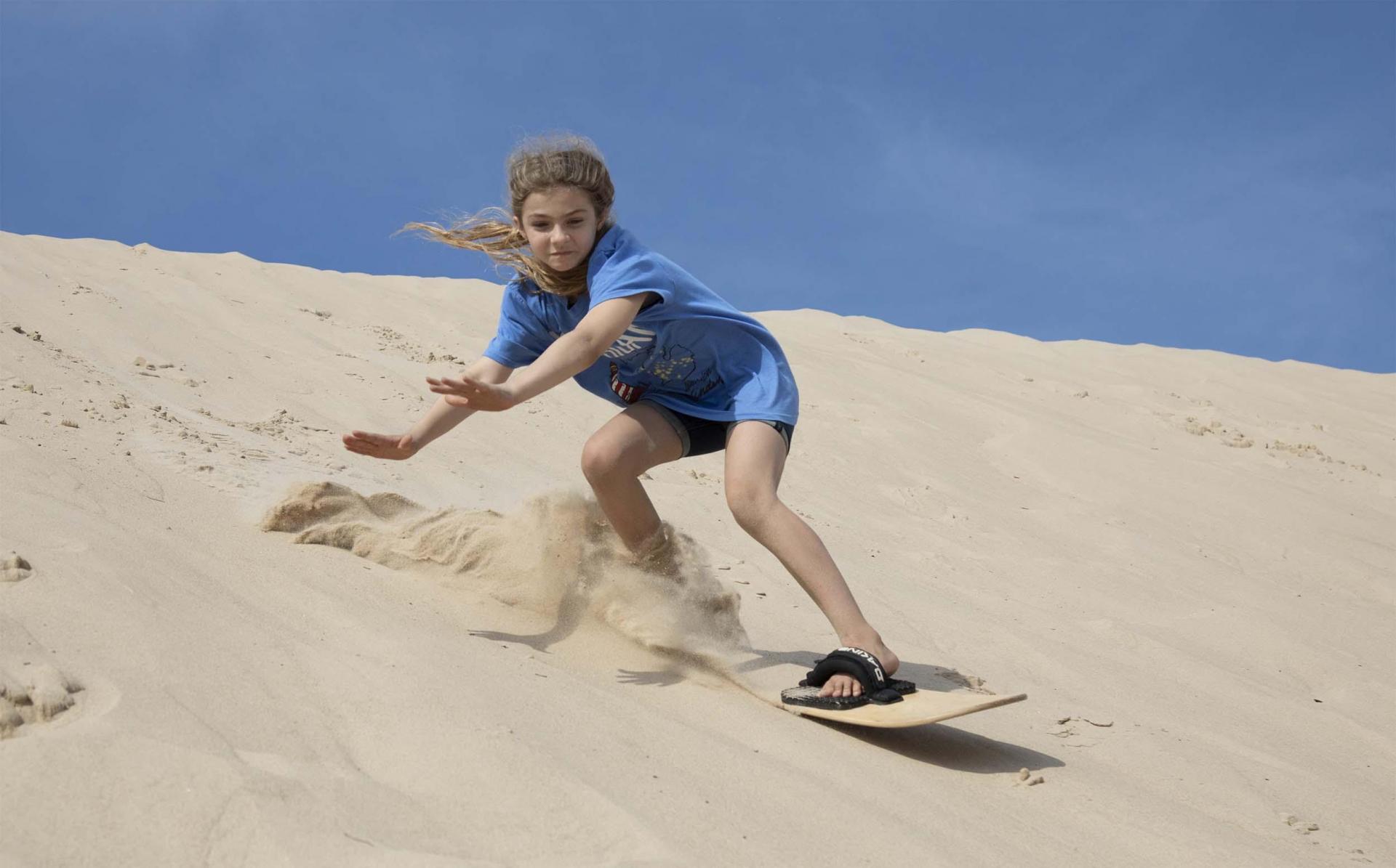 A person sand boarding at Warren Dunes State Park in the summer.