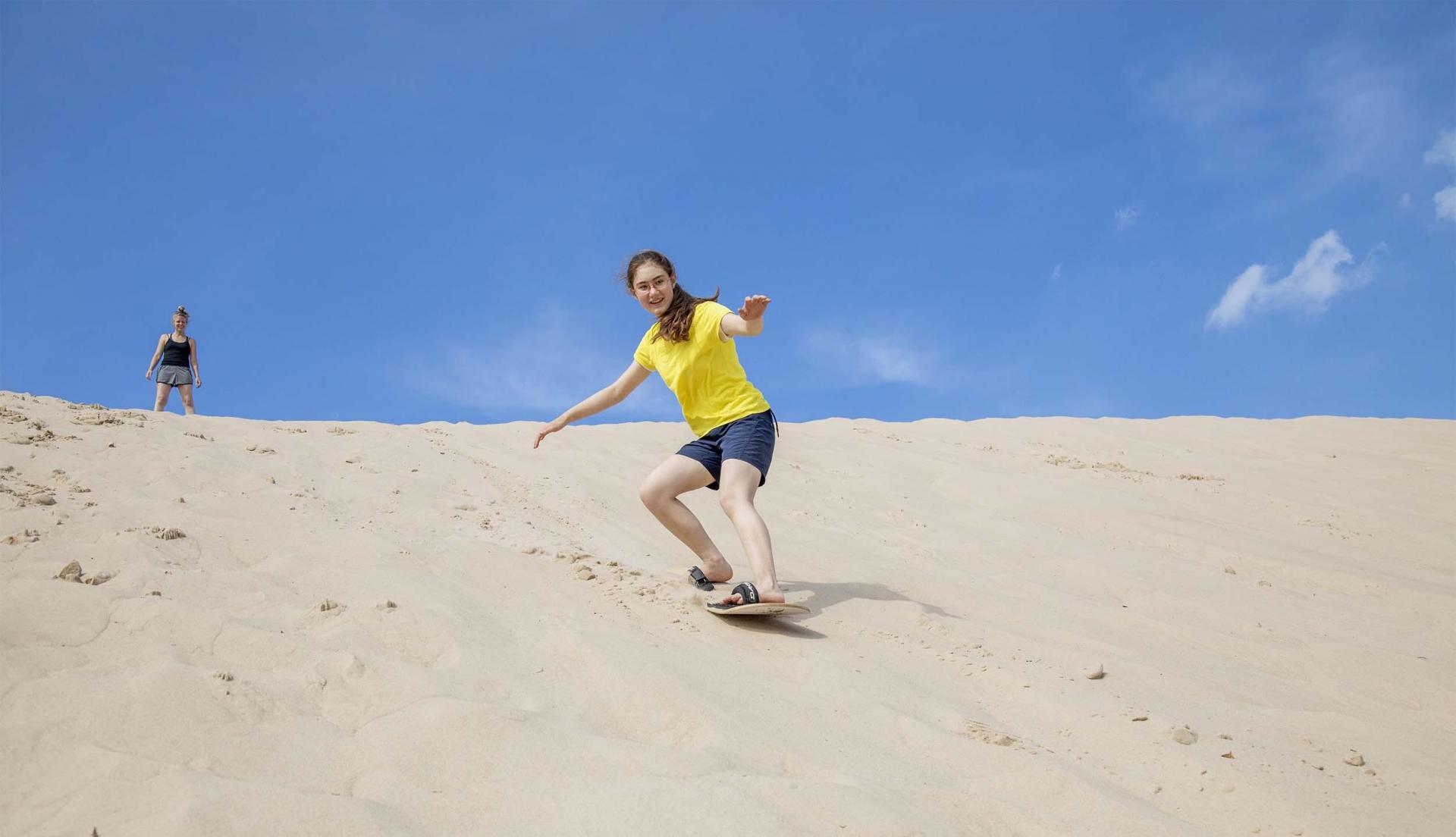 A person sand boarding at Warren Dunes State Park in the summer.