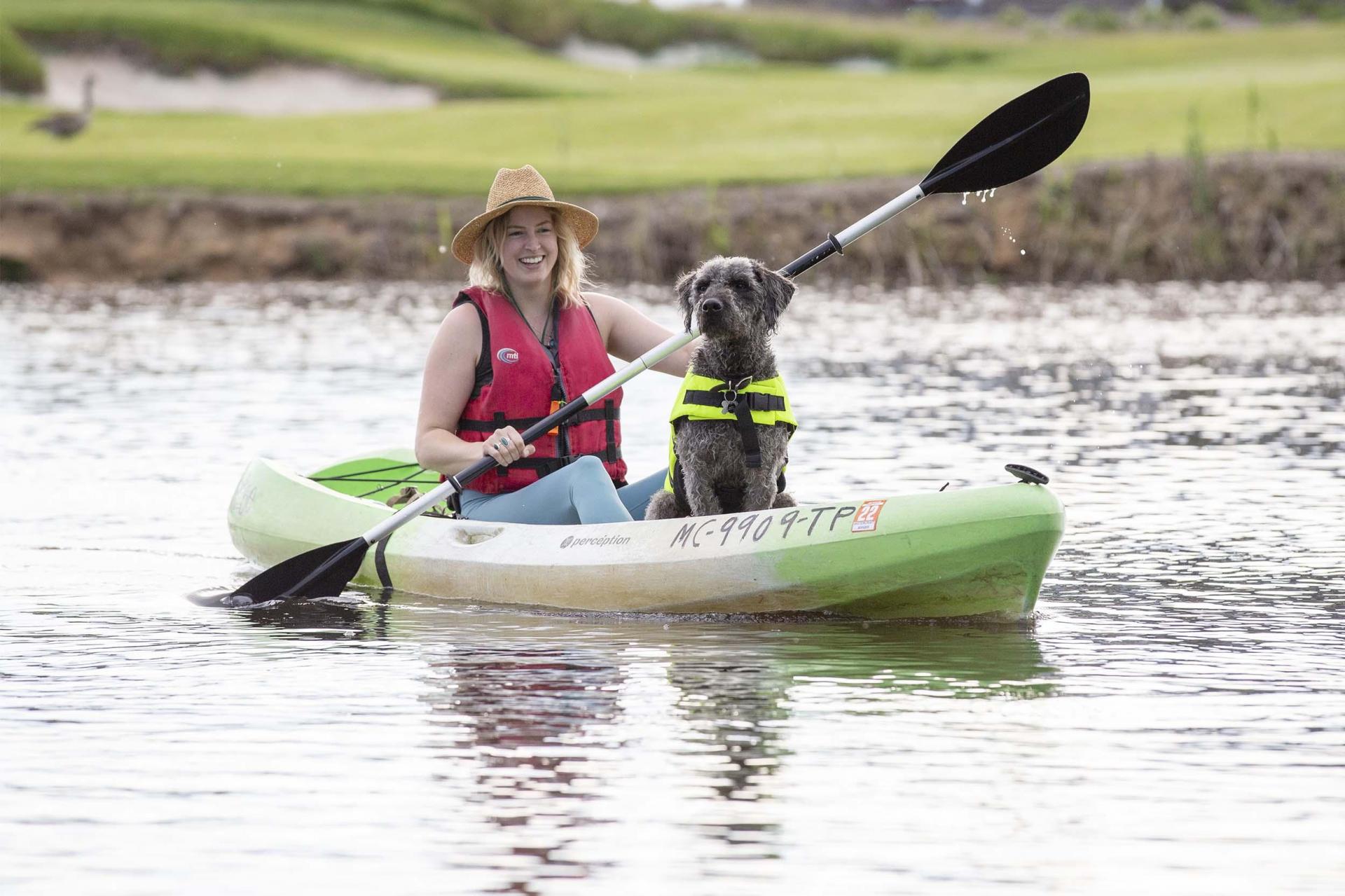 A person kayaking with a dog.