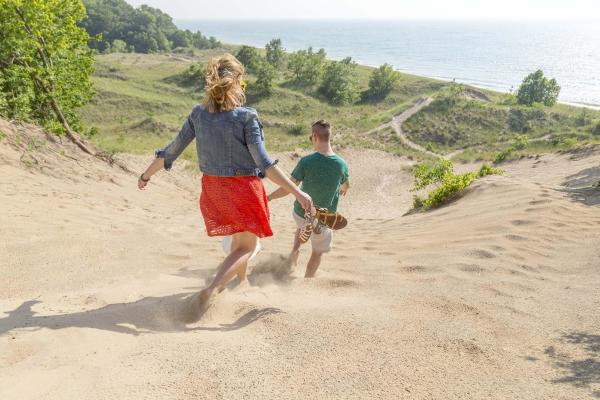 People running down a dune at Grand Mere State Park.
