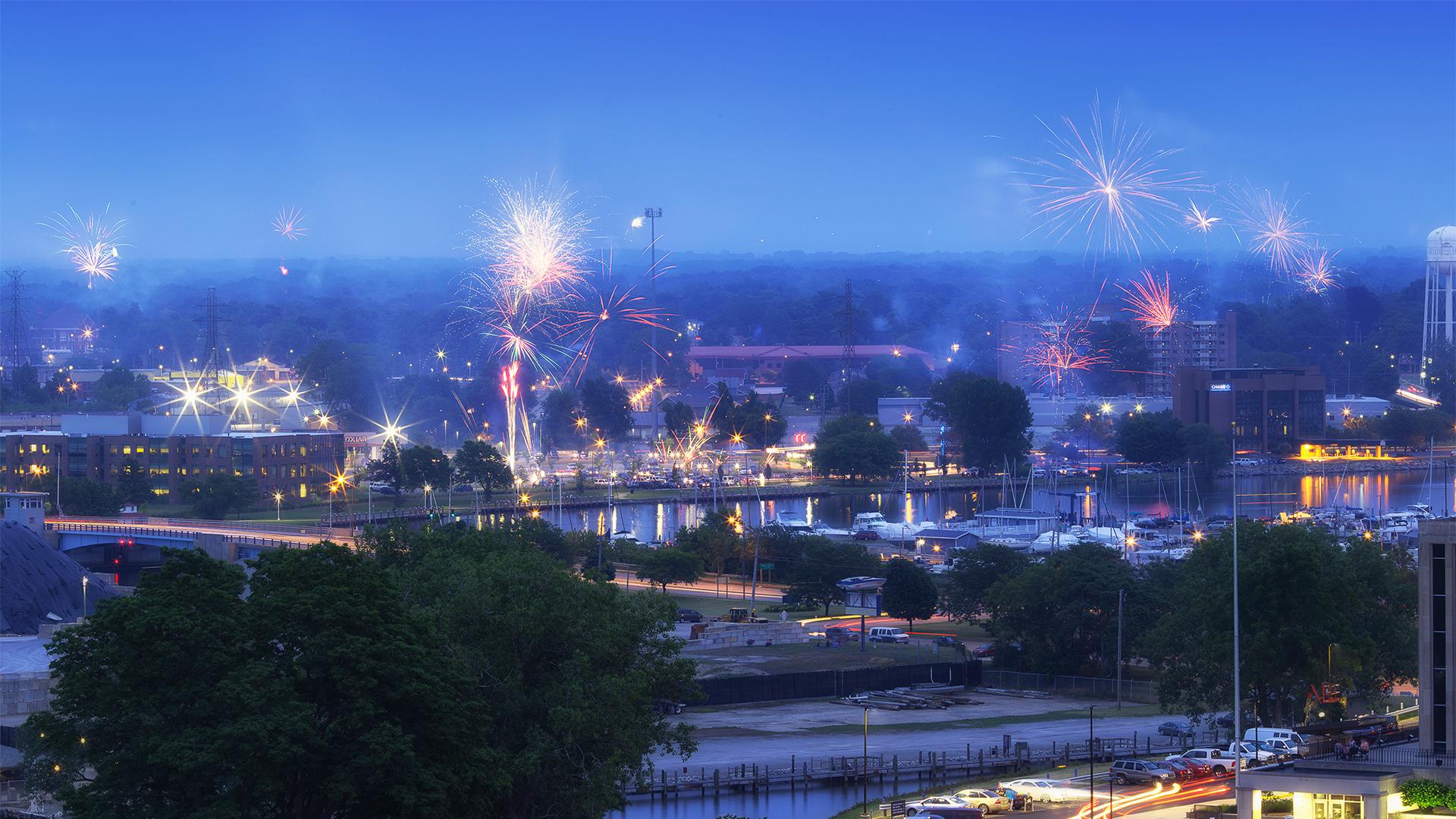 An overview shot of Fourth of July fireworks celebrations in Benton Harbor, with the river, boats, and docks visible in the background