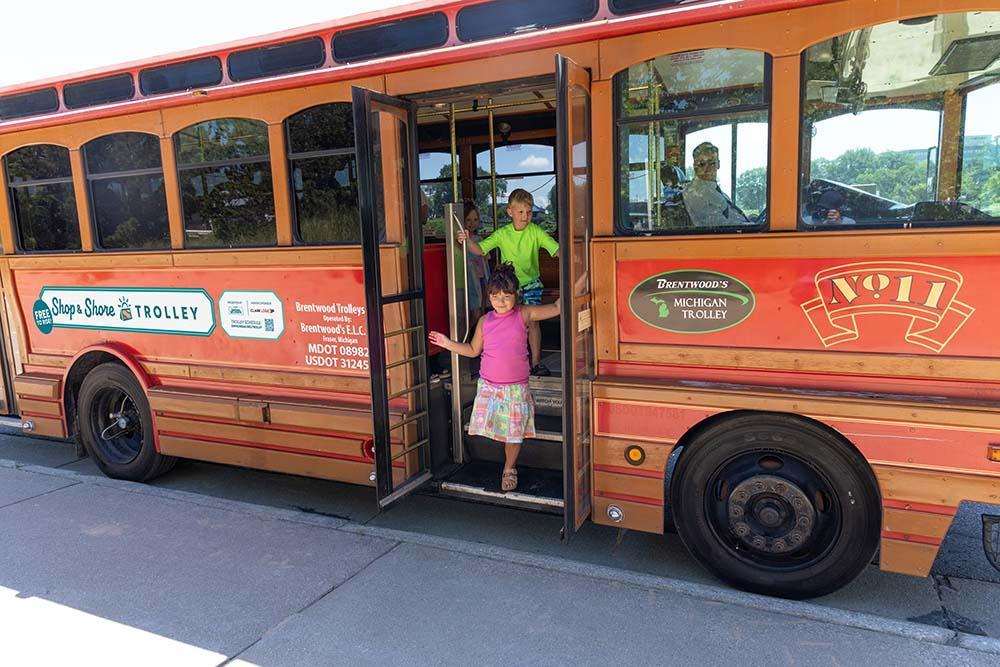 A family getting off of the Shop & Shore Trolley.