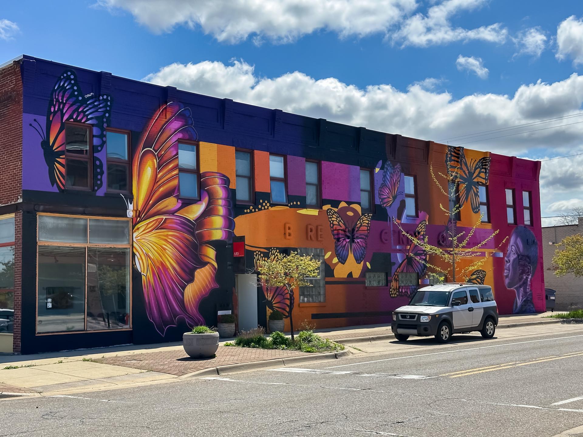 A Colorful mural with butterflies and a portrait of a young art student on the ARS Gallery building in the Benton Harbor Arts District