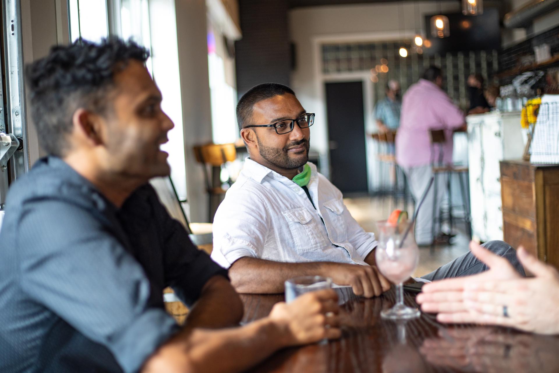 A group of guys talking at a table over drinks at the Iron Shoe Distillery.