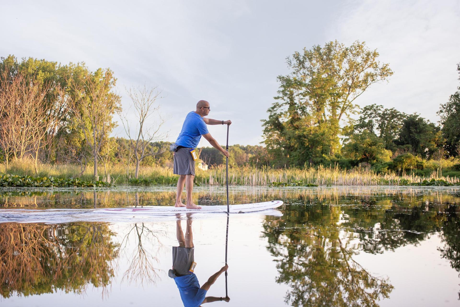 A man stand-up paddleboarding on the Galien River in the fall.