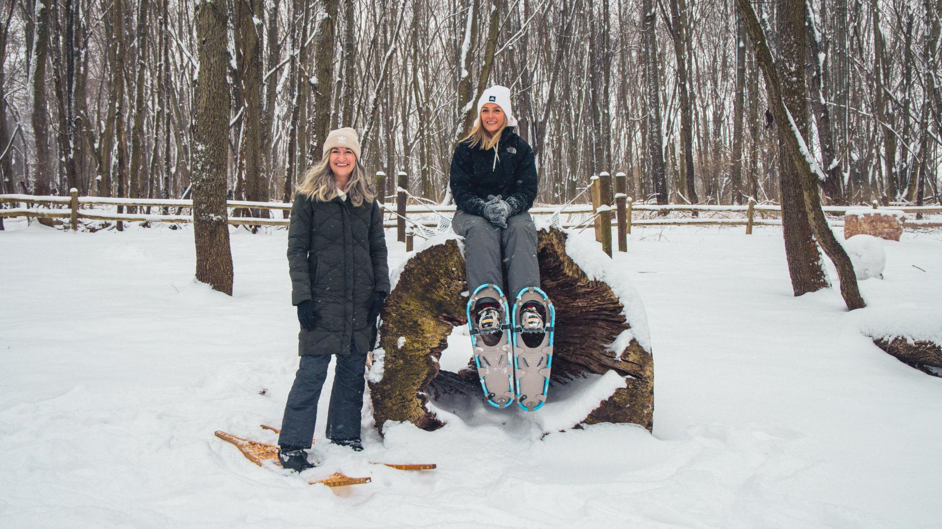 Two women pause for a photo while snowshoeing outdoors in winter at Sarett Nature Center.