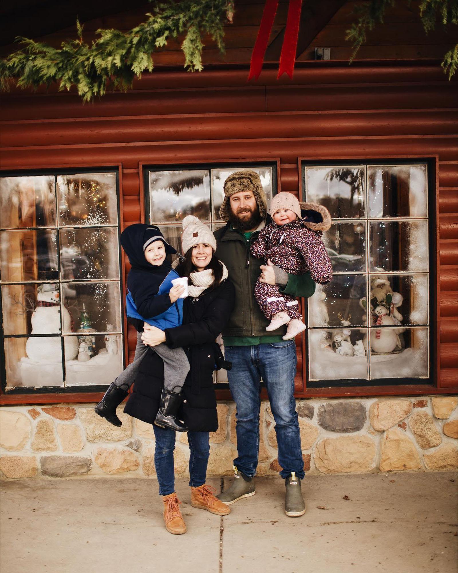 A family posing in front of a decorative holiday window.