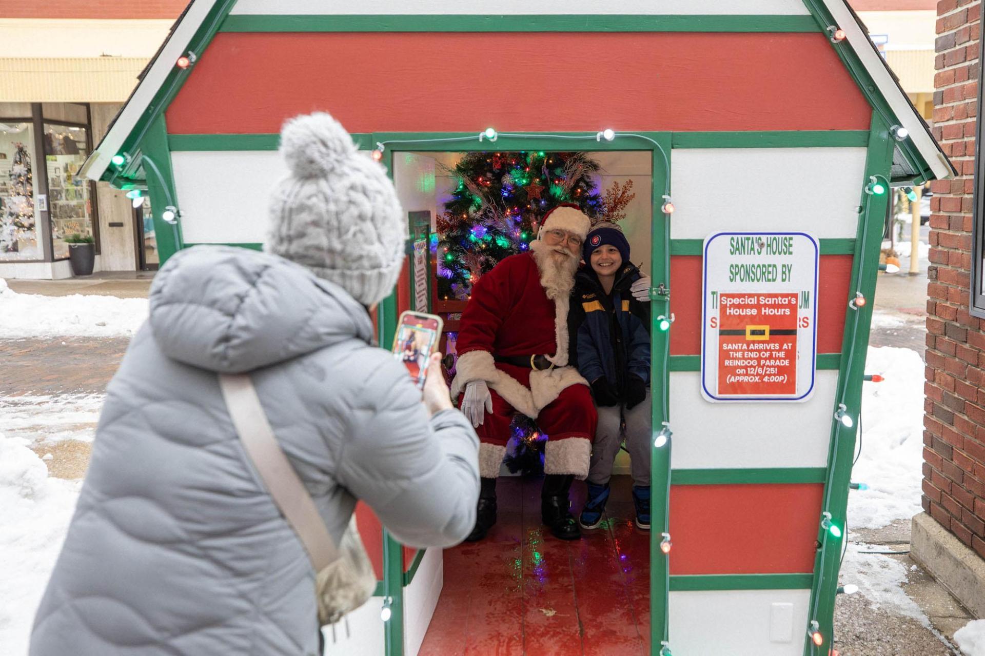A parent captures a photo of their child sitting with Santa.