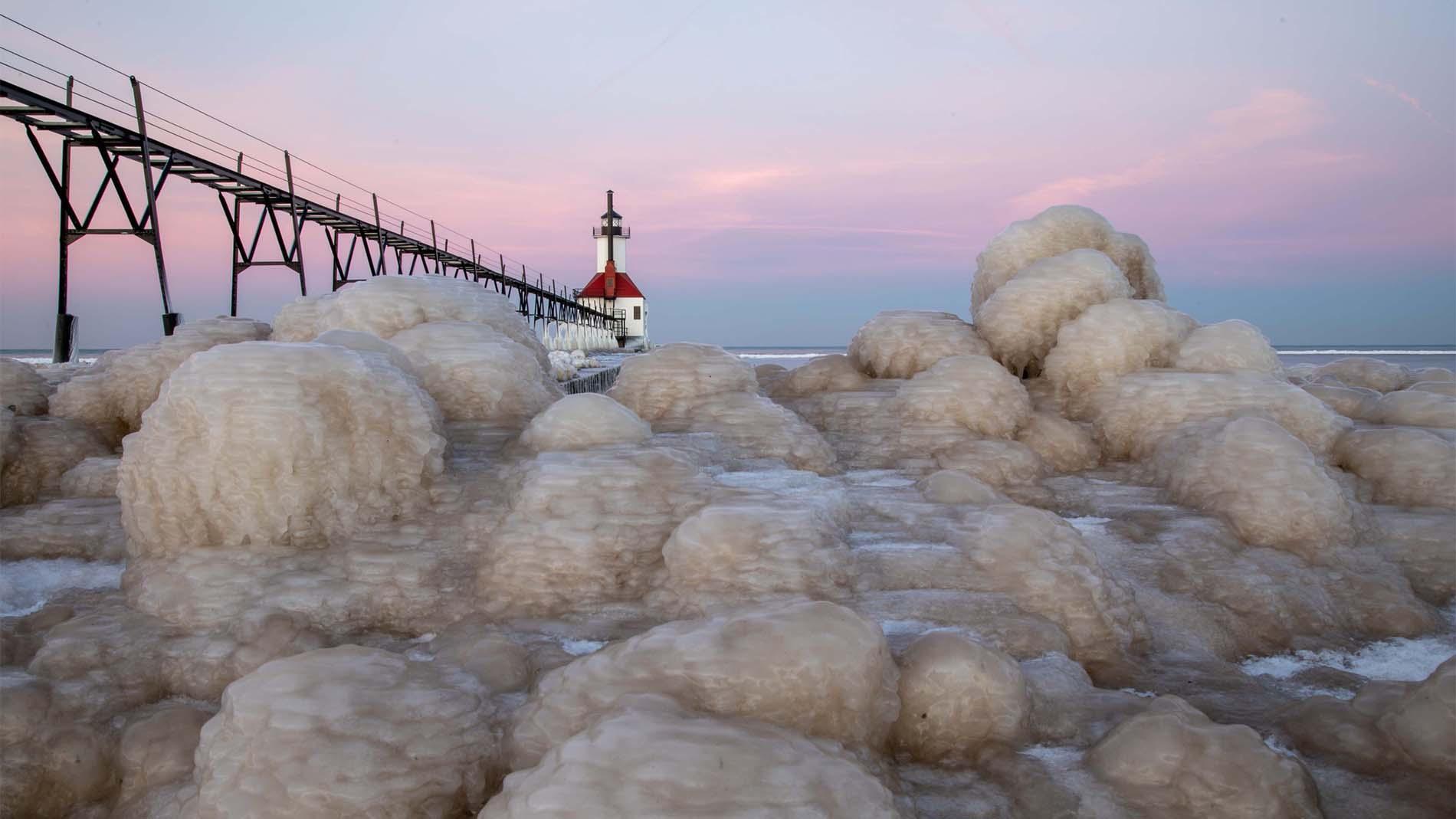 Ice accumulation near the pier with the lighthouse in the distance.