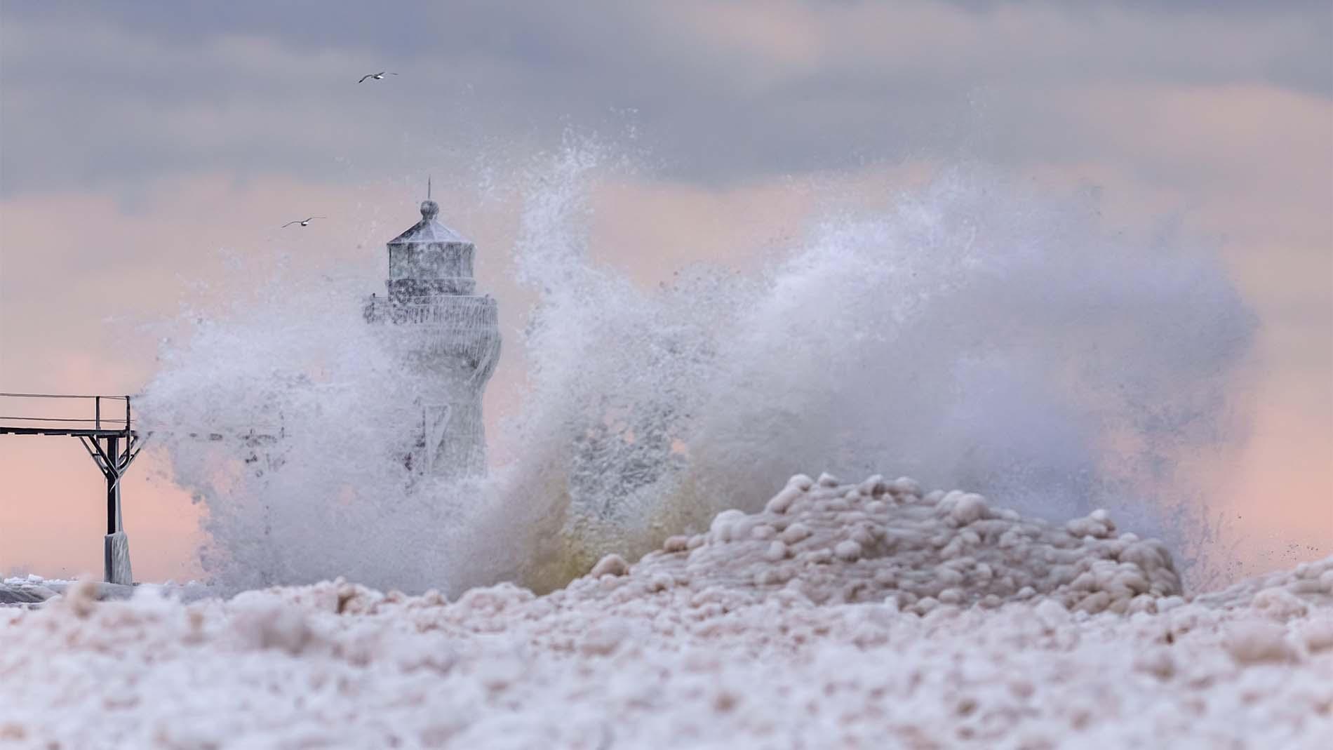 Waves crash as ice forms along the lakeshore and on the lighthouse in St. Joseph, MI.
