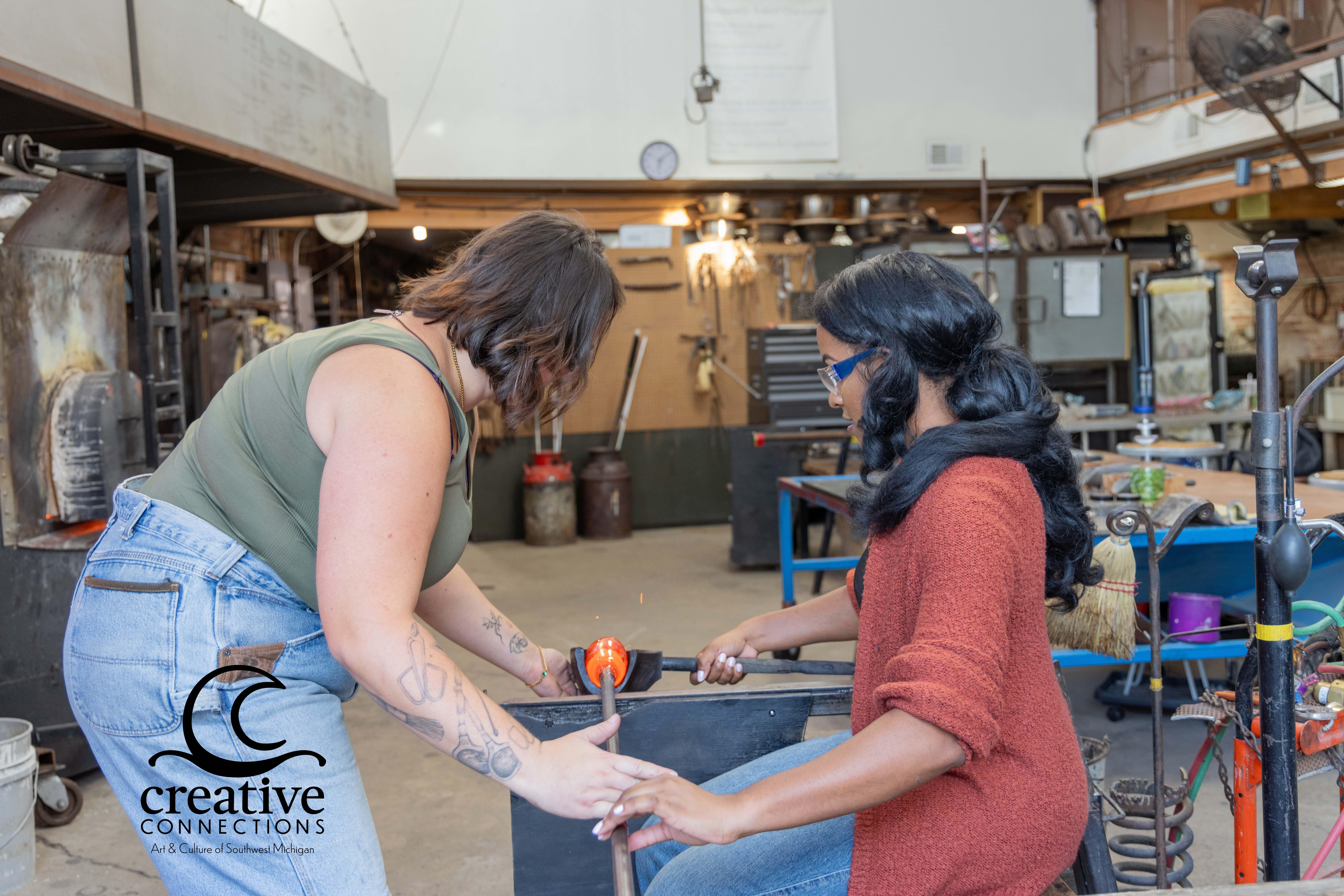 Glass art takes shape as two people work together at Water Street Glassworks.