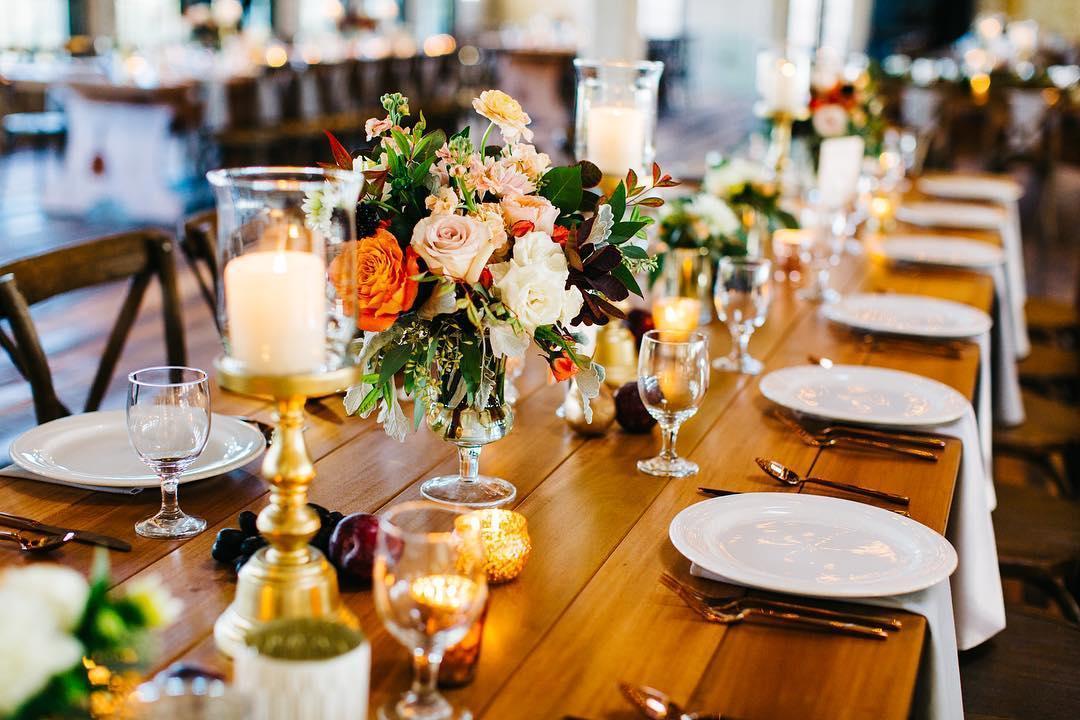 A wedding dining table arranged with décor and place settings.