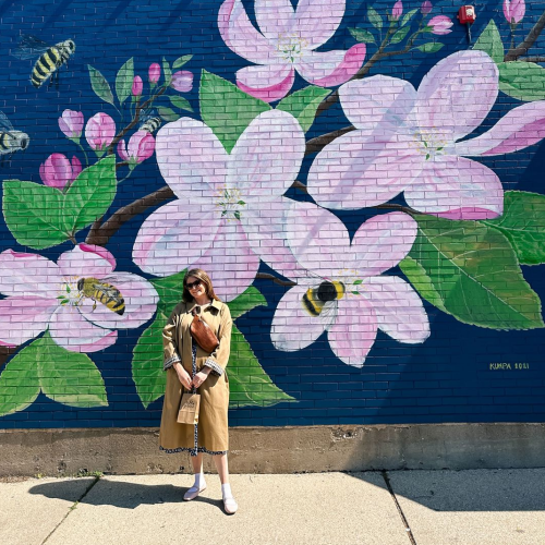 A person poses in front of the mural at Silver Harbor Brewing Company.