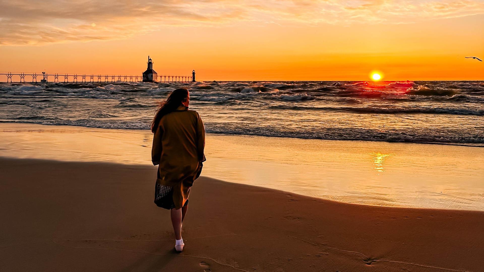 A person walks along the beach at sunset at Tiscornia Park.