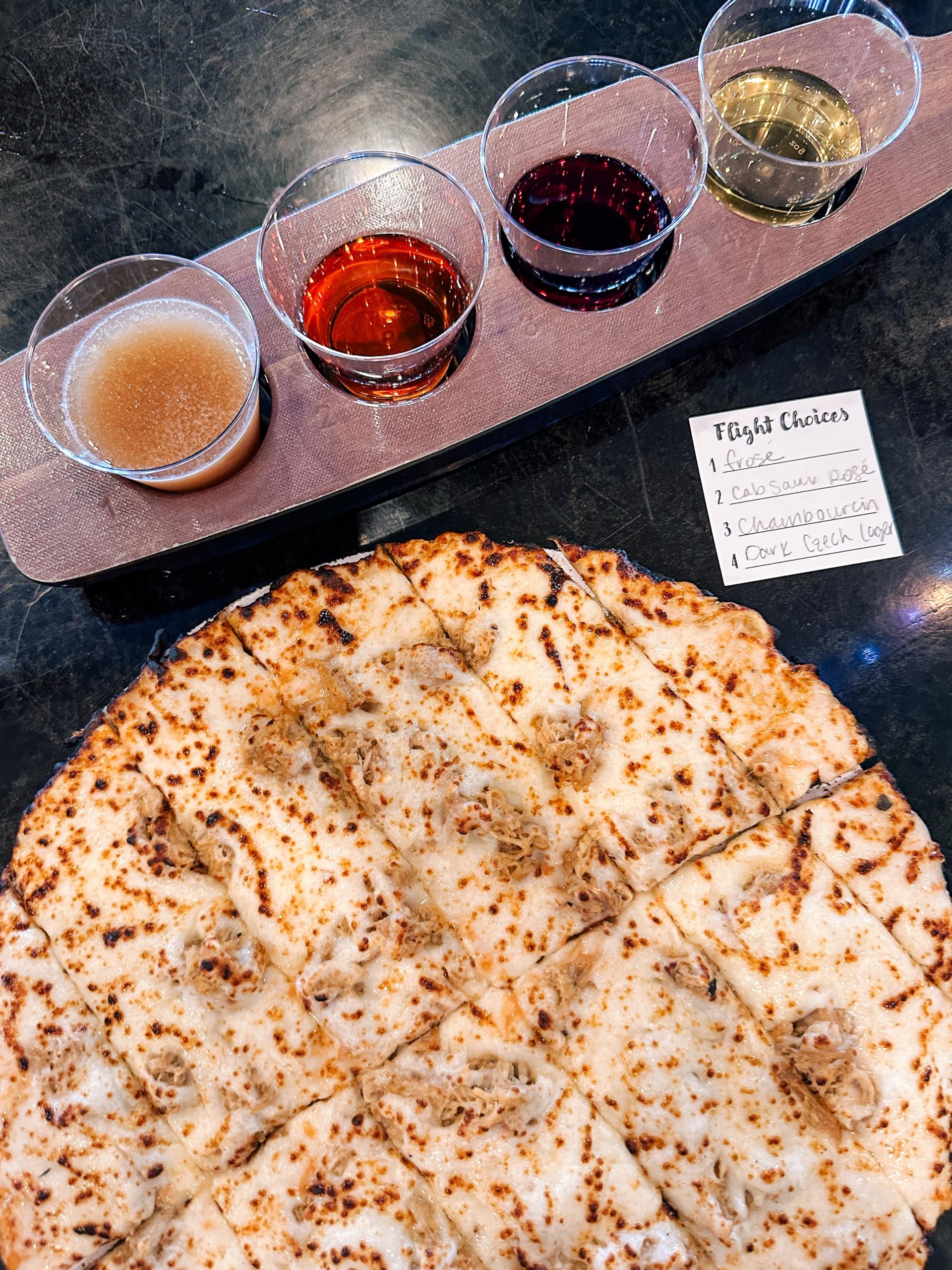 Pizza served alongside a flight of beer and wine.