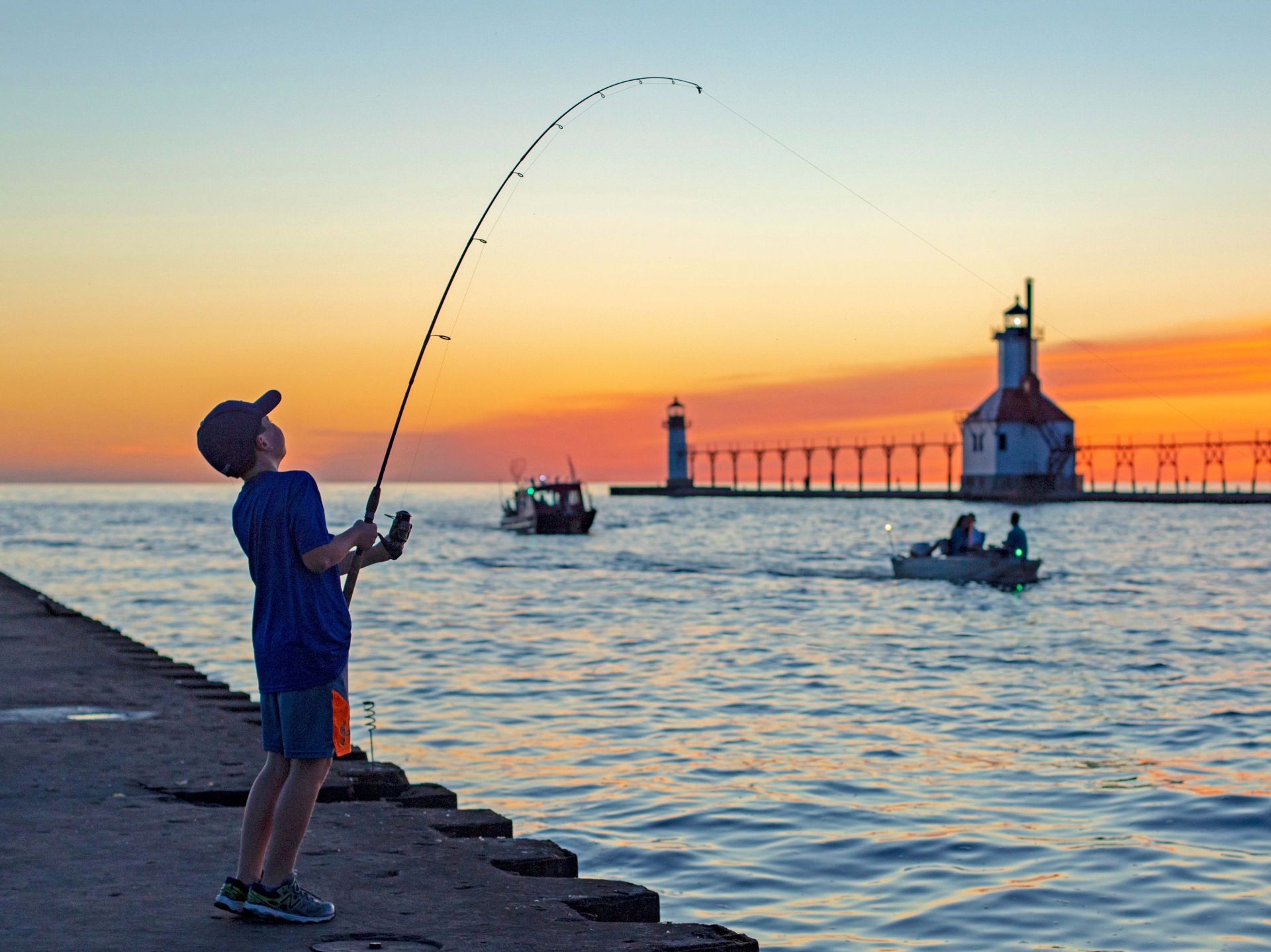 A-boy-fishing-near-the-lighthouse-at-sunset