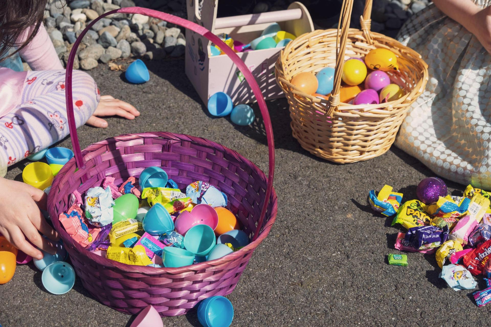 Children opening Easter eggs from their baskets after an egg hunt.