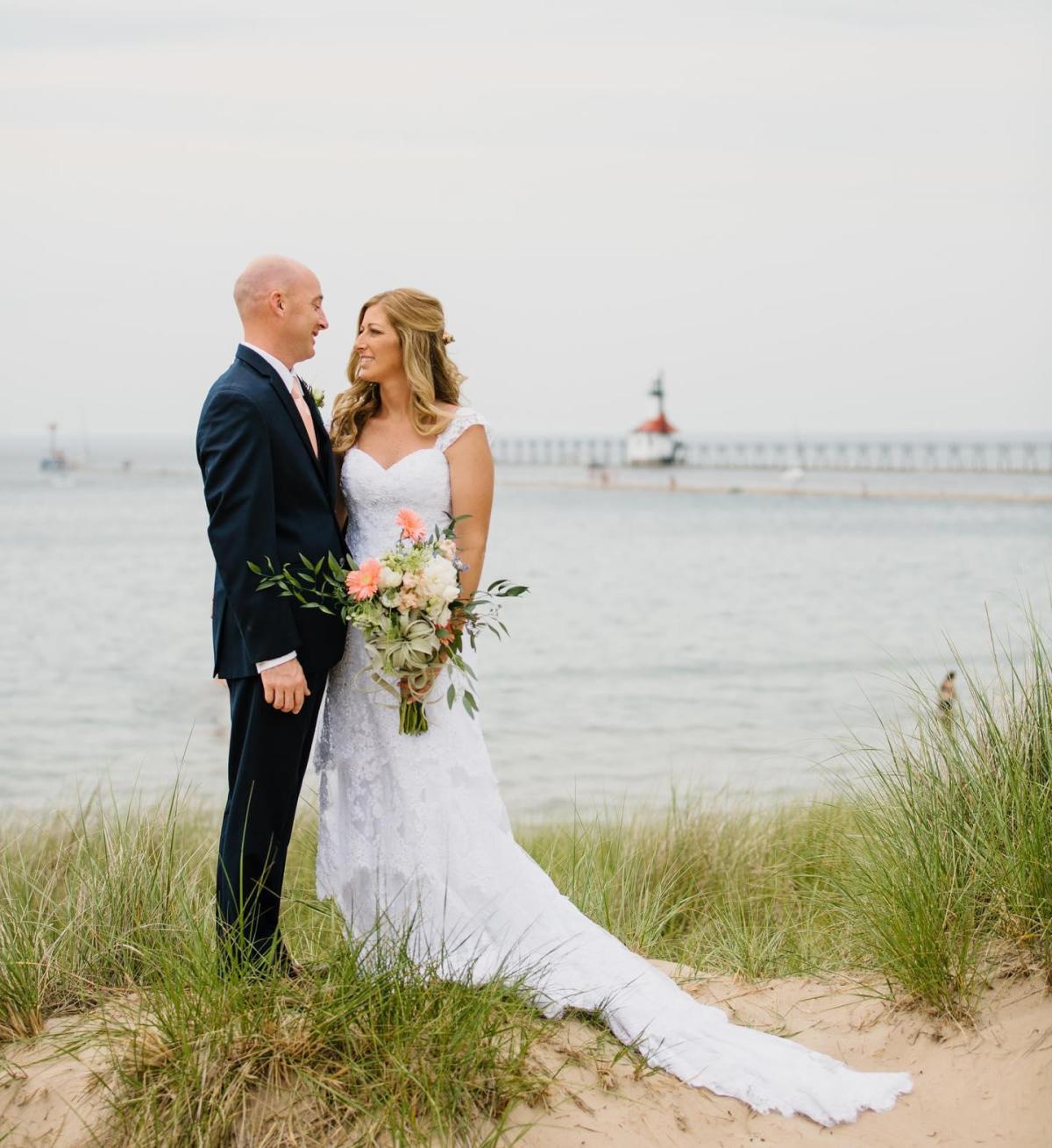 A bride and groom together on the beach in front of the St. Joseph Lighthouse