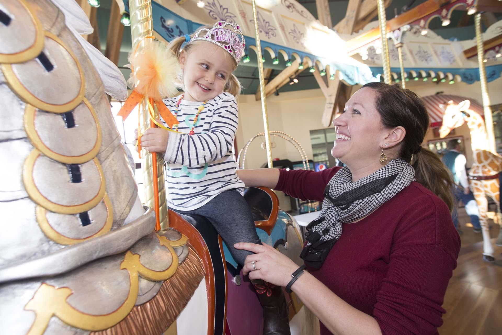 An adult and child on the carousel. 