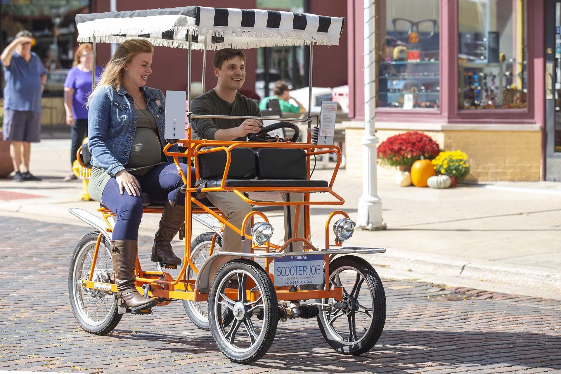 A couple riding a surrey bike.