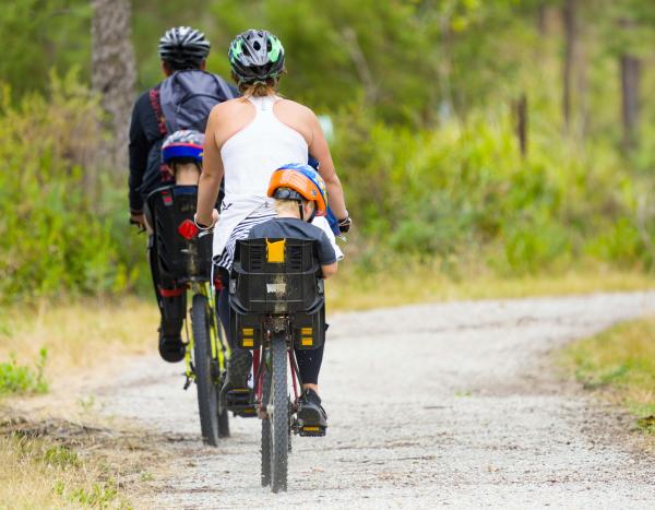 A family bikes along a wooded trail.