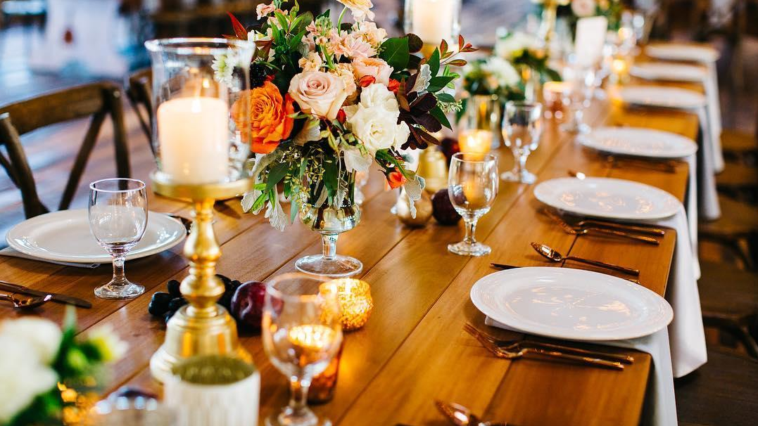 A wedding dining table arranged with décor and place settings.