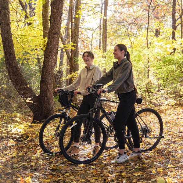 Two women smiling on the trails holding bikes