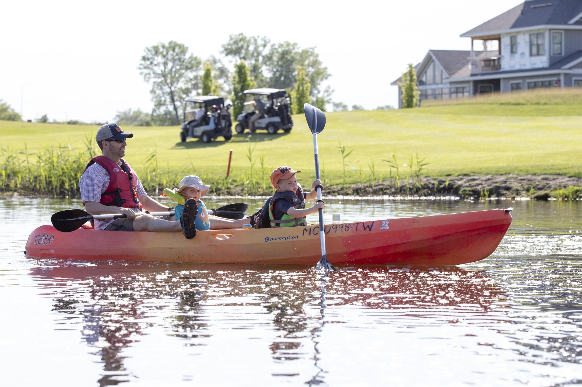 A father and two children kayak past Harbor Shores Golf Club on the Paw Paw River.
