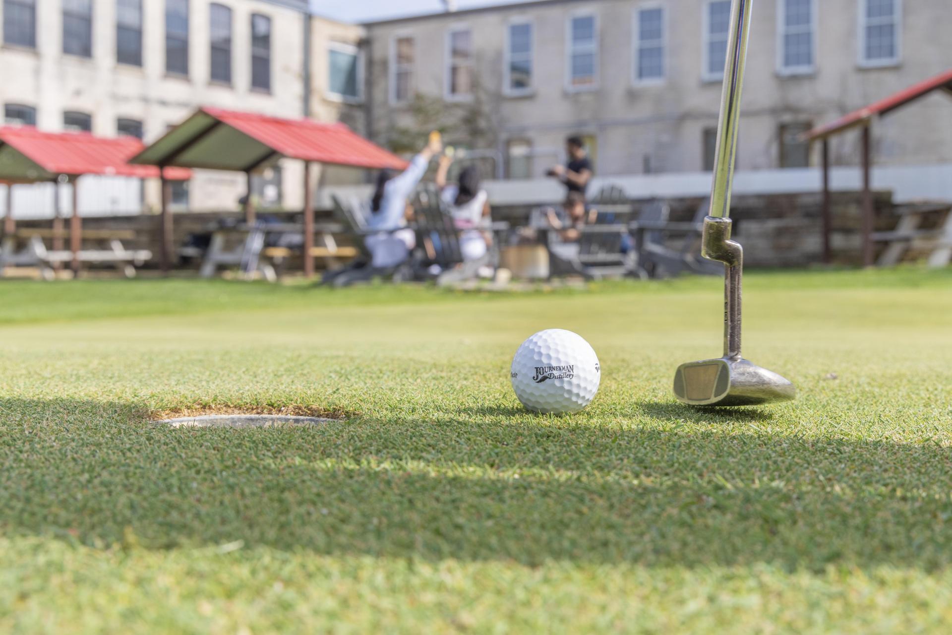 A person lines up a putt at Welter’s Folly at Journeyman Distillery.