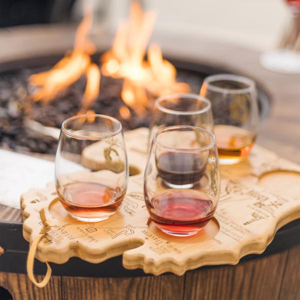 Short wine glasses on a Michigan wood shaped tray, with a firepit in the background