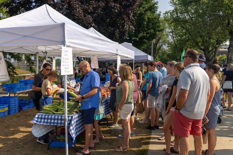 Group of people at the farmers market in line for corn