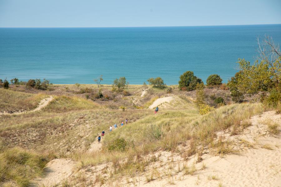 Warren Dunes, people walking through some sand dunes to get to the beach, Lake Michigan in the background.