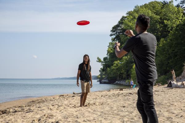 Two people playing with a frisbee on the beach, Lake Michigan behind them.