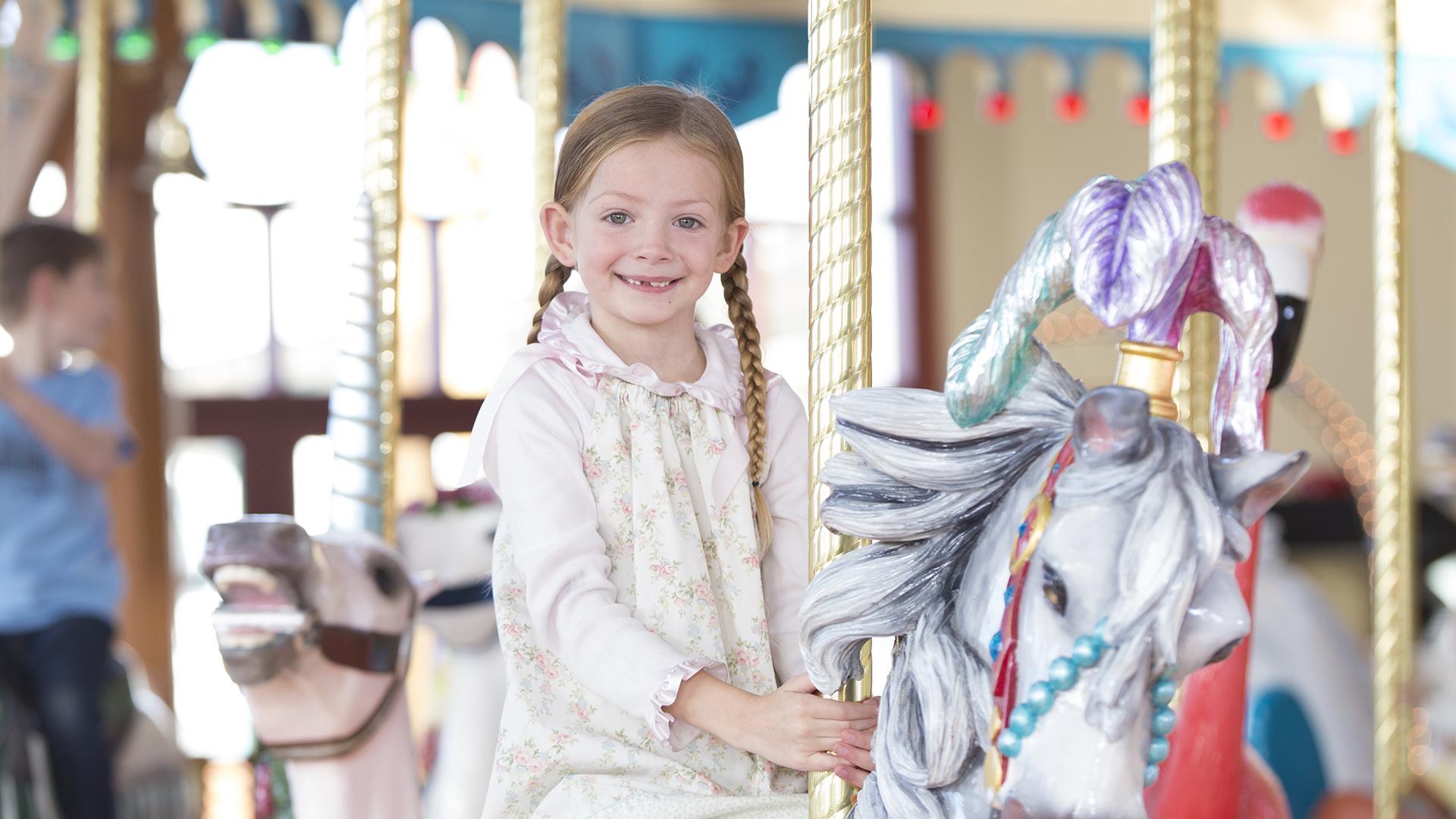 A child riding the Silver Beach Carousel.