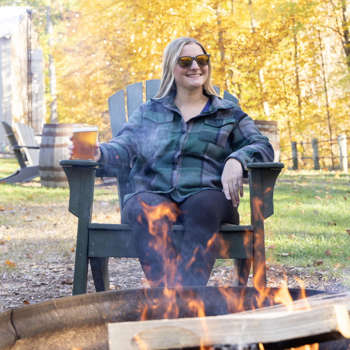 A person enjoys a beer beside an outdoor fire at Haymarket Brewery.