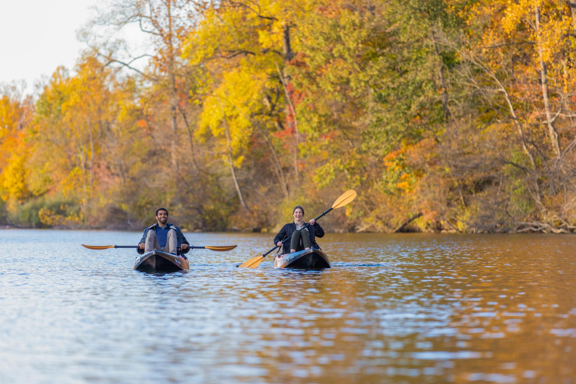 A couple kayaks along the St. Joseph River, surrounded by vibrant fall colors.
