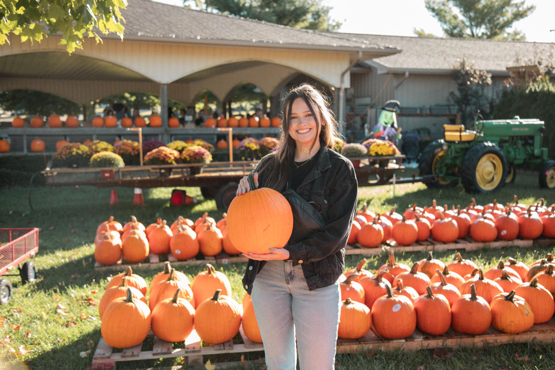 A woman poses for a photo with the pumpkin she selected.