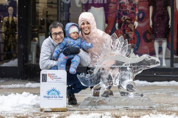 Family posing by a dinosaur ice sculpture
