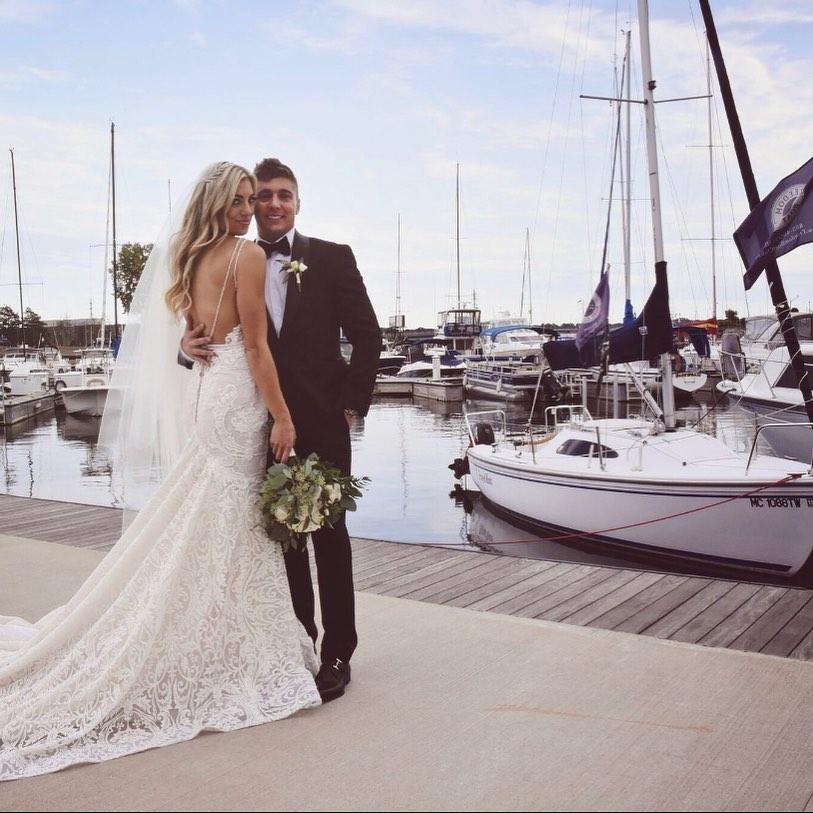 A couple standing near sailboats.