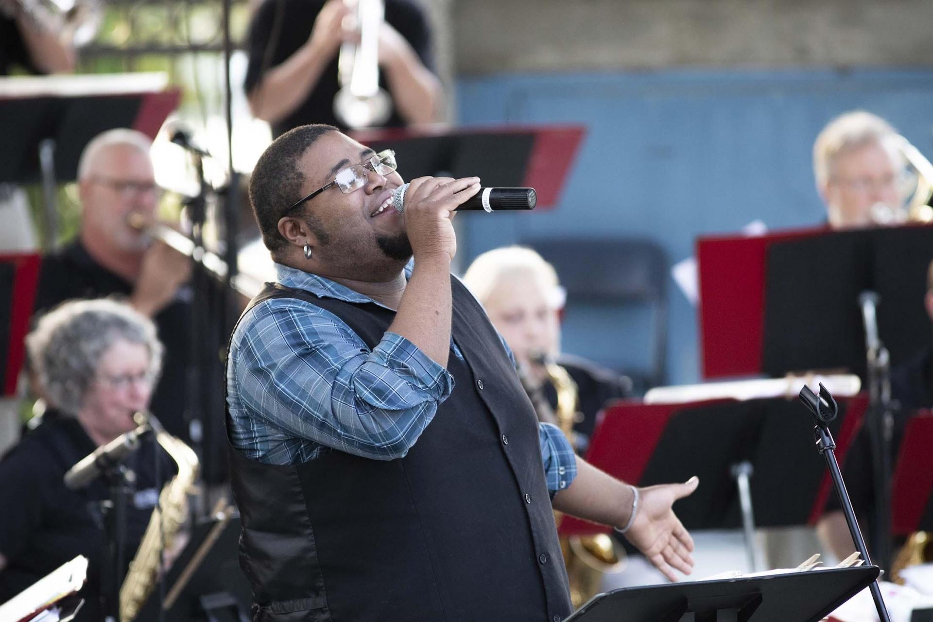 Andrew Fisher singing at an outdoor concert.