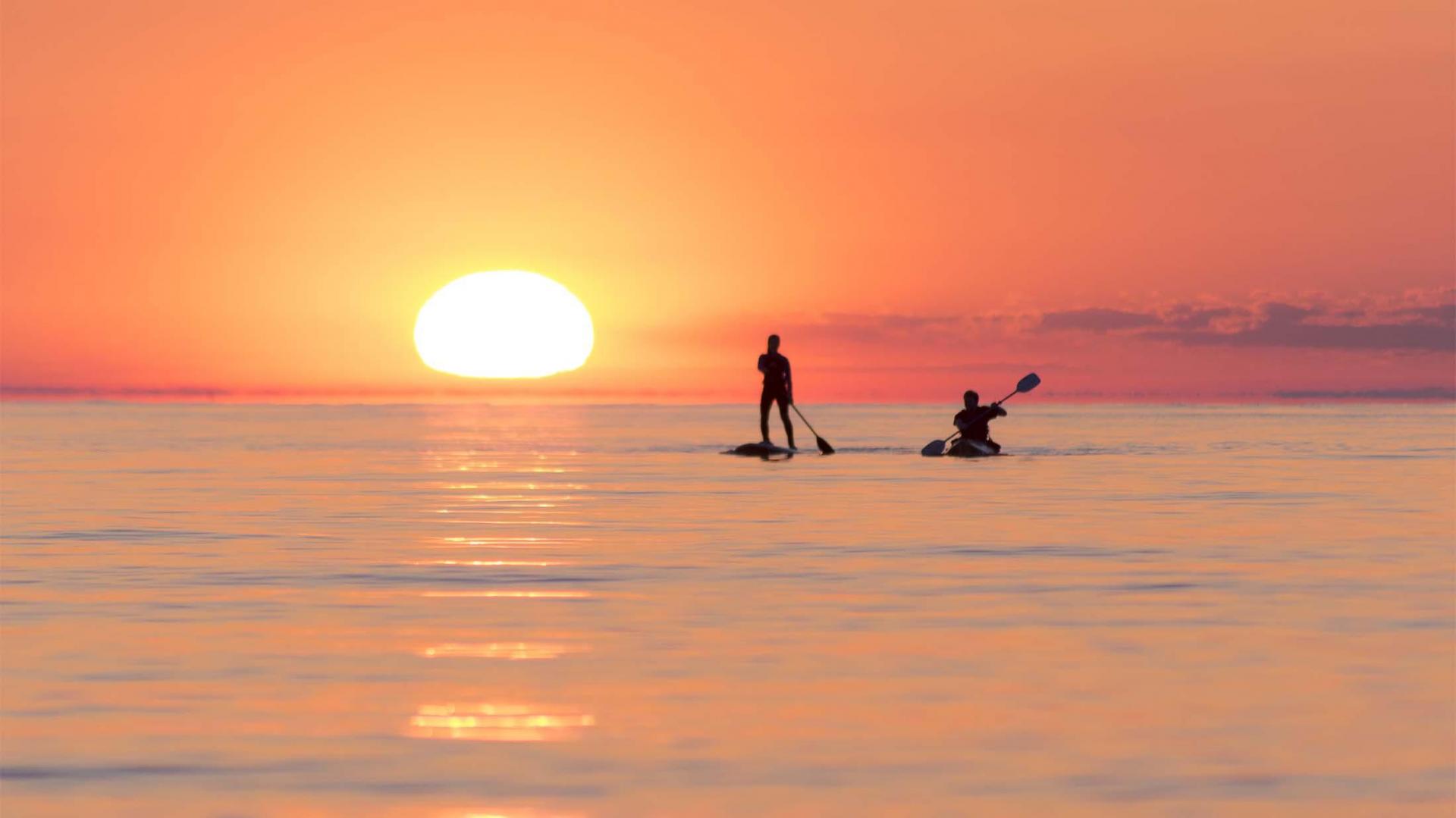 Two people paddling at sunset on Lake Michigan.