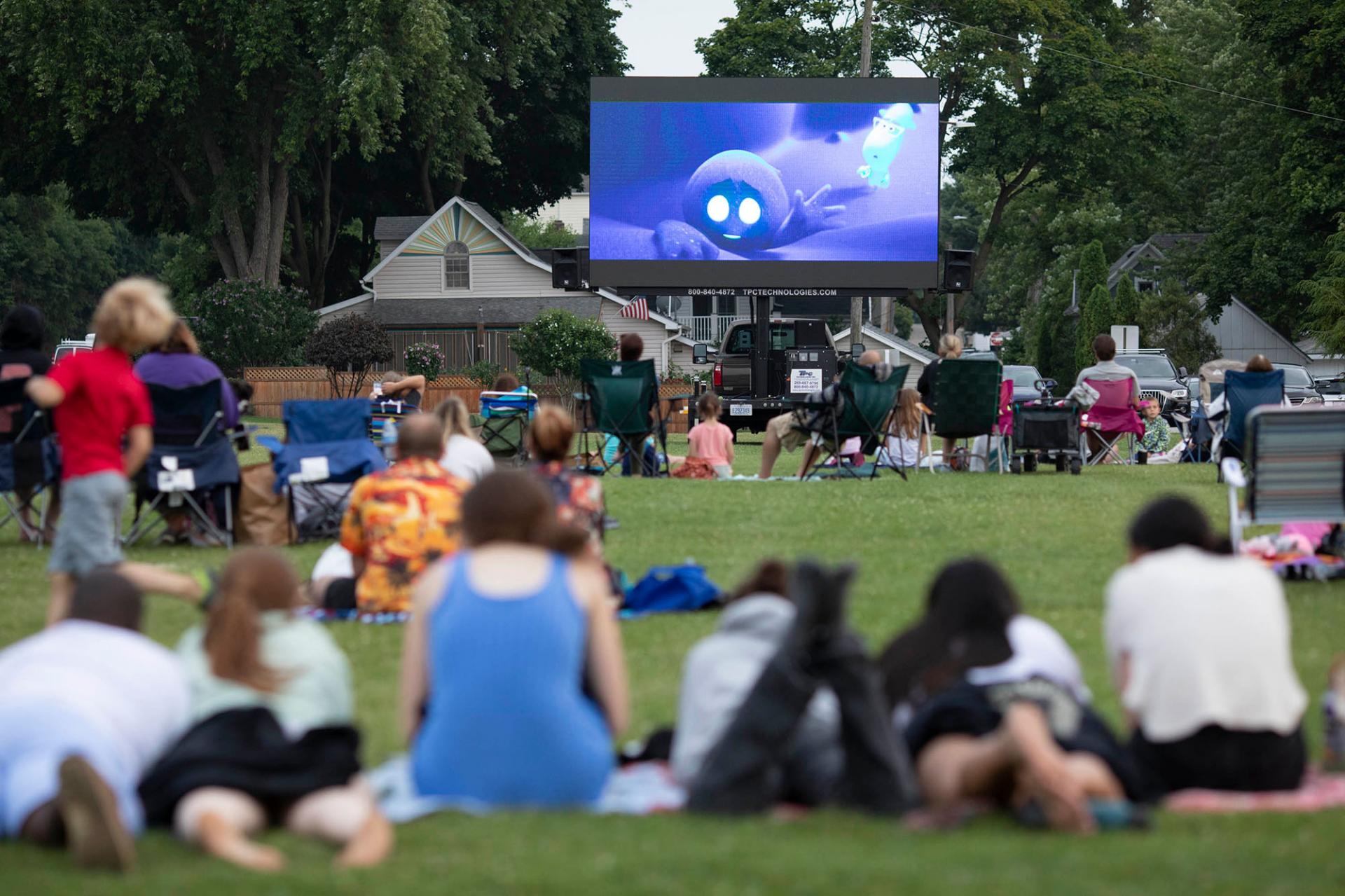 A group of people watching a movie in the park